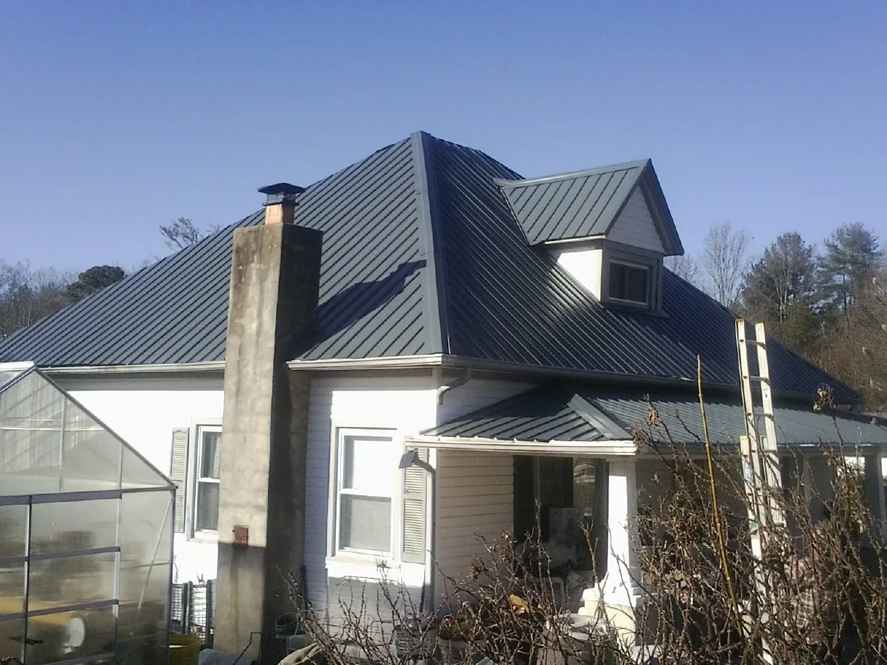 Dark blue standing seam metal roof on a white farmhouse with dormer — Slate & Tile Roof Repair by Roofing Brothers in Newport